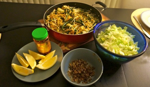 Mee goreng with lettuce, lemon wedges, sambal oelek, and fried shallots