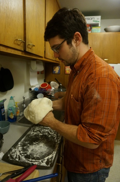 Max rolling out the pizza dough onto the baking pan
